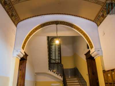 Gli stessi elementi decorativi tornano ad abbellire la parte interna di un arco che precede le scale e poggia su dei capitelli a volute